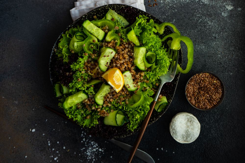 Top view of green fresh salad on concrete background with copy space