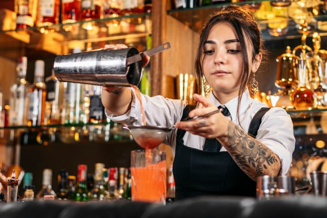 Female bartender preparing a cocktail in a traditional cocktail bar