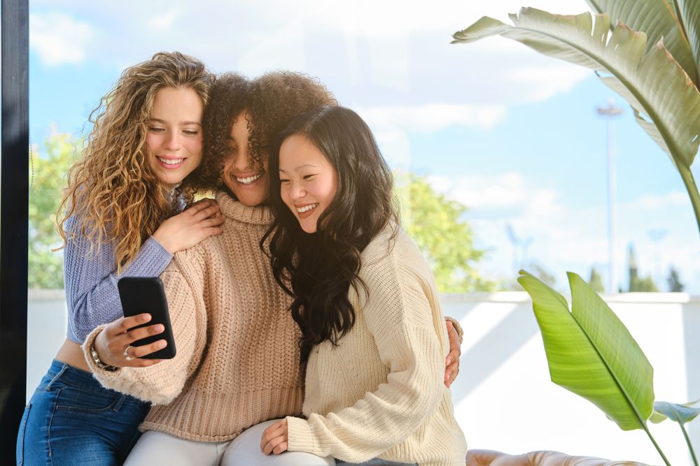 Multiracial girlfriends embracing and taking selfie