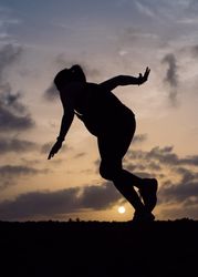 Jumping woman and sky with clouds at sunset