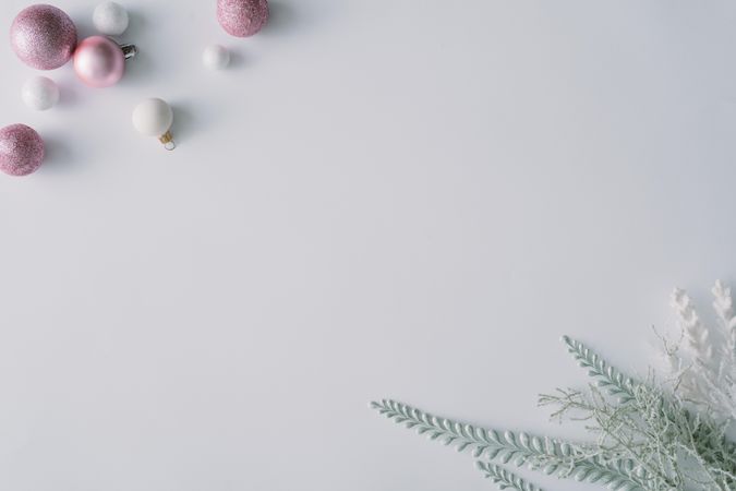Pink baubles and snowy leaves in corners of light background