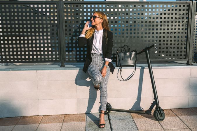 Businesswoman with mobile and her scooter next