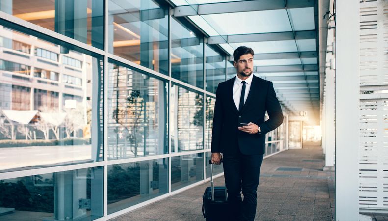 White male business traveler with suitcase at airport