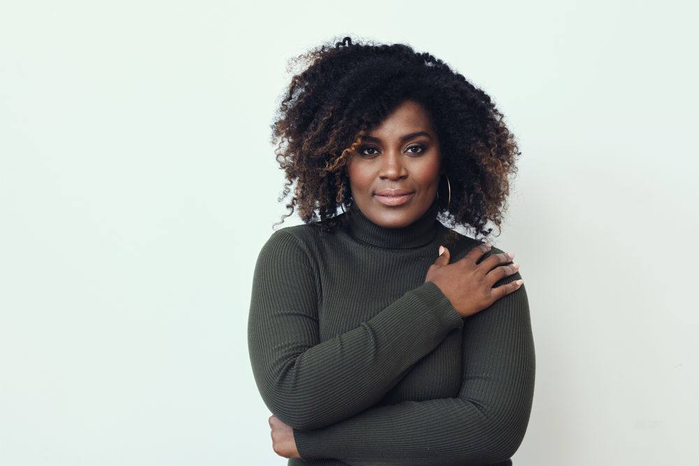 Black woman looking at camera with her hand on her shoulder
