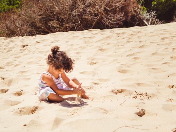 Cute little girl playing with sand at beach