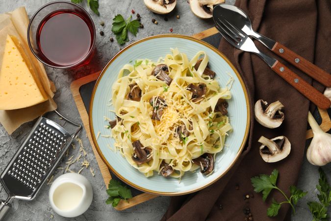 Composition with plate of tasty pasta and ingredients for cooking on gray background