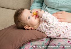 Cute baby lying on woman's lap with pacifier 0PxQl0