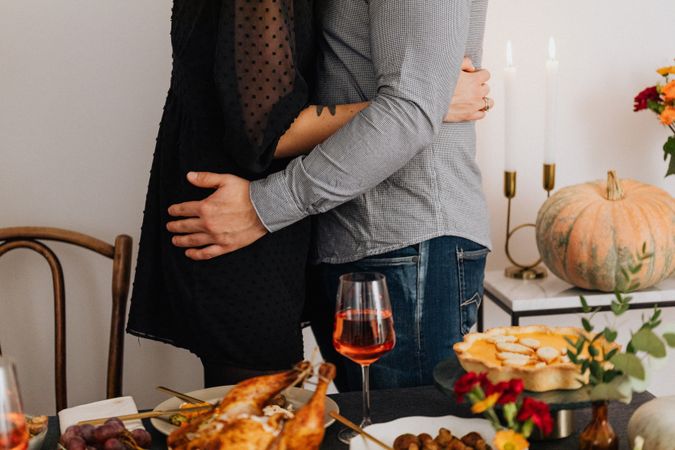 Cropped image of couple hugging each other beside dinner table
