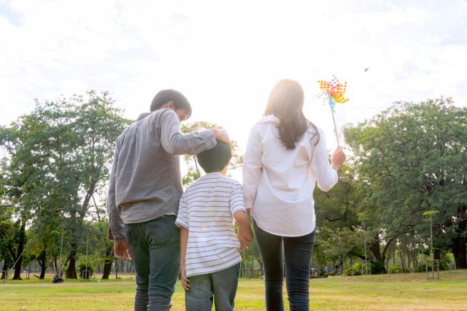 Father with hand on son’s head with mother holding child's hand in park