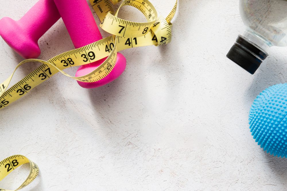 Dumbbells, Massage Ball, Water Bottle And Measuring Tape on Fitness-Inspired Background