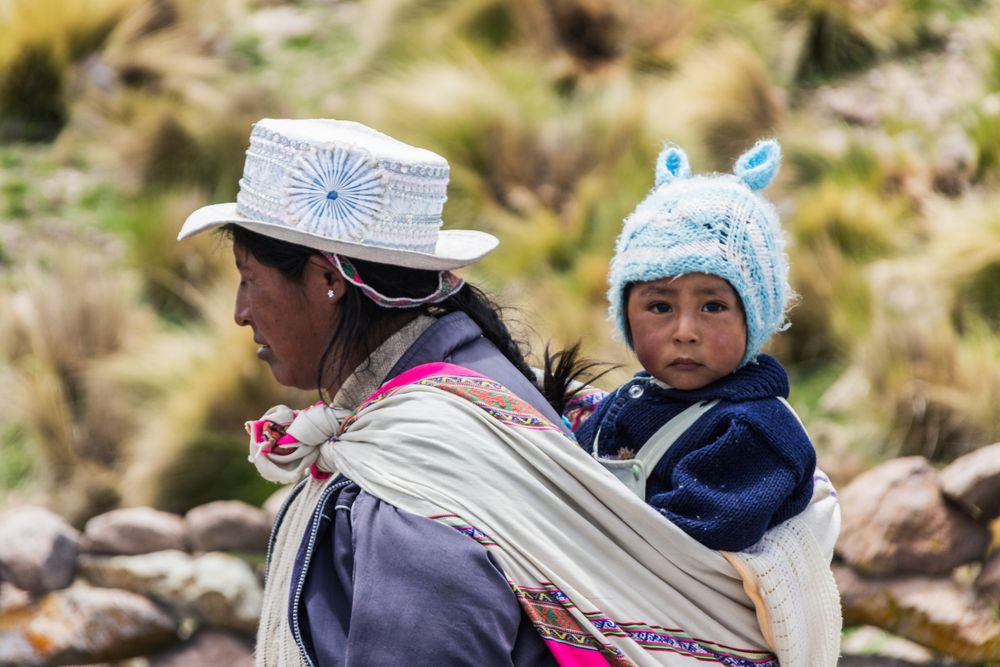 Peru - January, 02 2012: Peruvian woman carrying baby on back