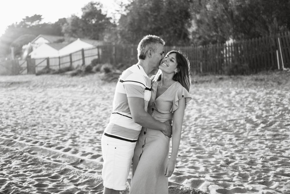 Laughing couple hugging on sandy beach