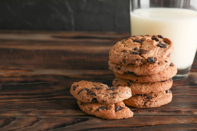 Tasty chocolate chip cookies and glass of milk on wooden table. Space for text