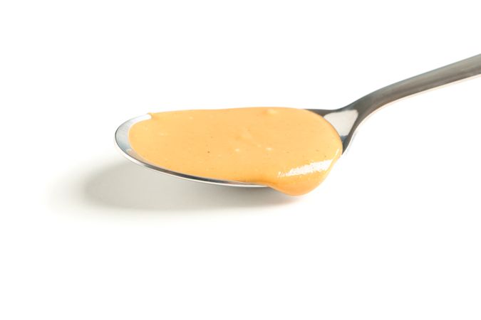Creamy peanut butter in spoon isolated on bright background, closeup. A traditional product of American cuisine