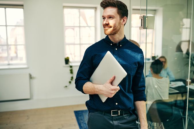 Portrait of man holding laptop in the office
