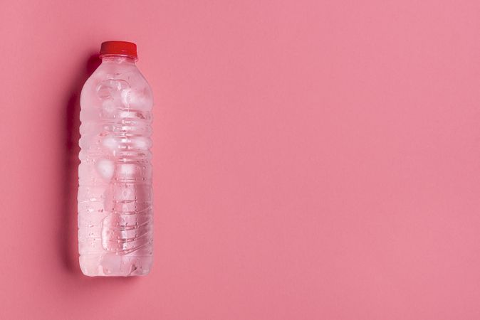 Ice cold water bottle with pink background