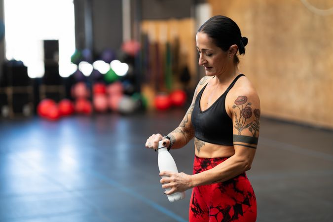 Woman about to drink water after training in gym