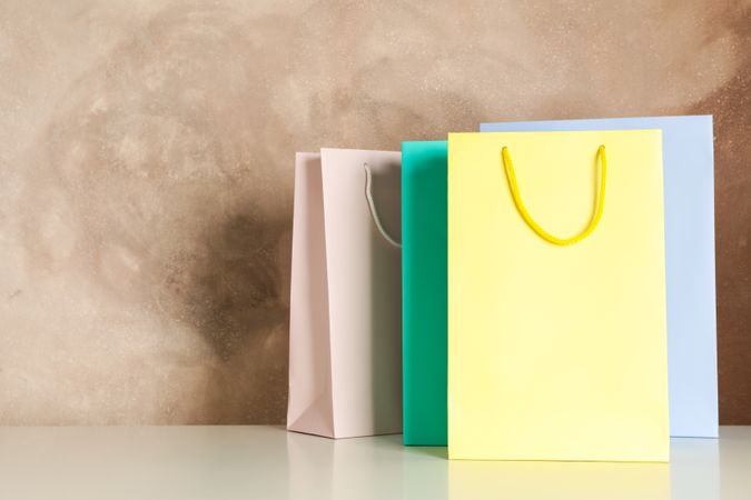 Color bags on table against brown background, copy space