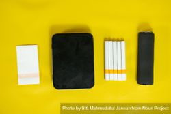Top view of yellow table with cigarettes and papers 426MZ3