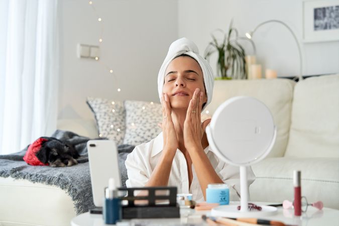 Relaxed woman doing massage with facial cream while recording vi