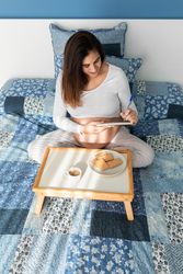 Pregnant woman having breakfast and taking notes in notepad