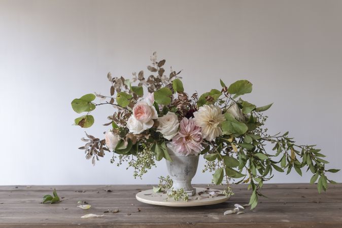 Composition of flowers and plants in vintage vase on board