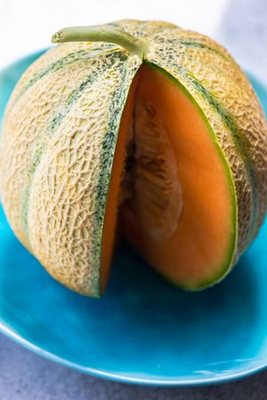 Whole melon with chunk cut out on blue plate