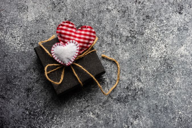 Felt heart ornaments on top of small dark giftbox