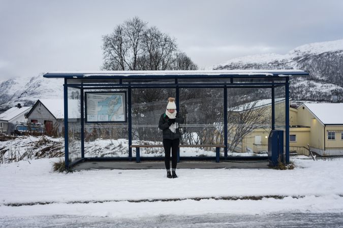 Asian woman waiting for bus in snowy outdoors