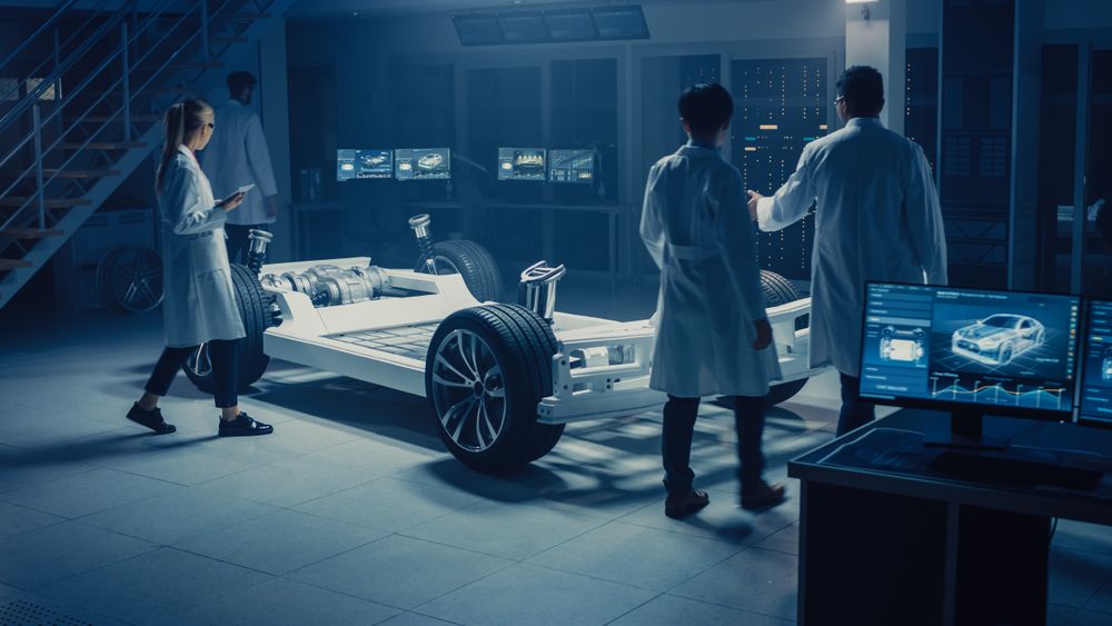 Team of Automotive Engineers and Scientists Discussing, Designing and Working on Electric Car Platform Chassis Prototype.