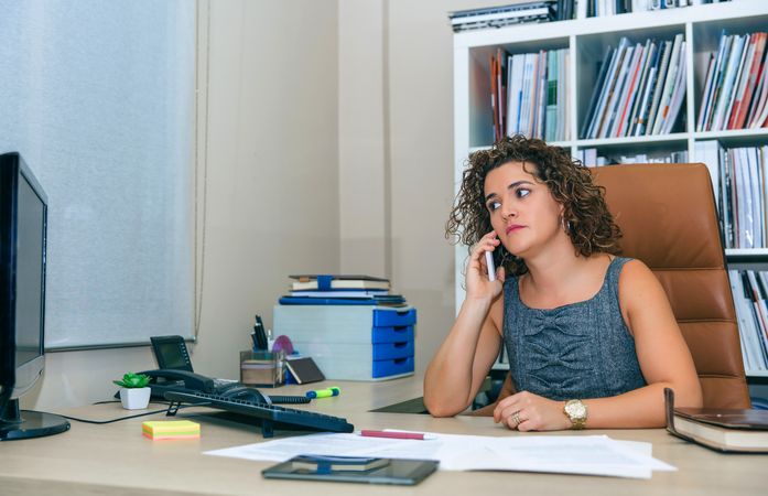 Businesswoman looking up from calendar in office with bookcase