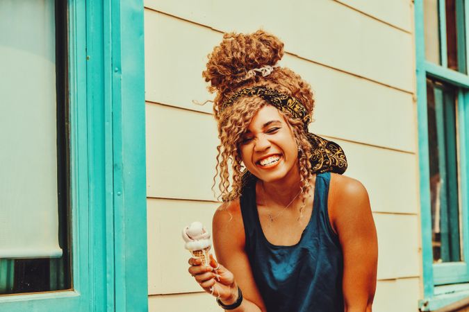 Amused Black female snacking on an ice cream cone in the sun