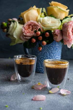 Side view of two espressos with bouquet of roses