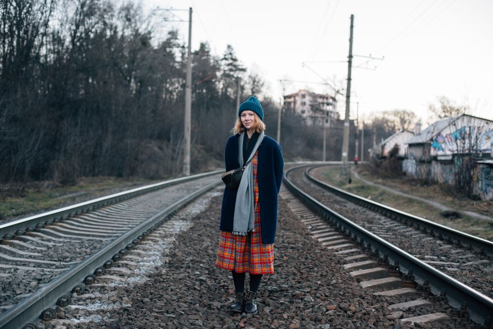 Woman in skirt and navy jacket in between train tracks