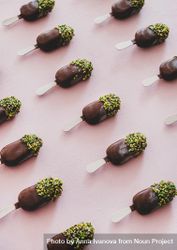 Diagonal rows of ice cream chocolate pistachio popsicles, pink background, vertical composition bDEqJ0