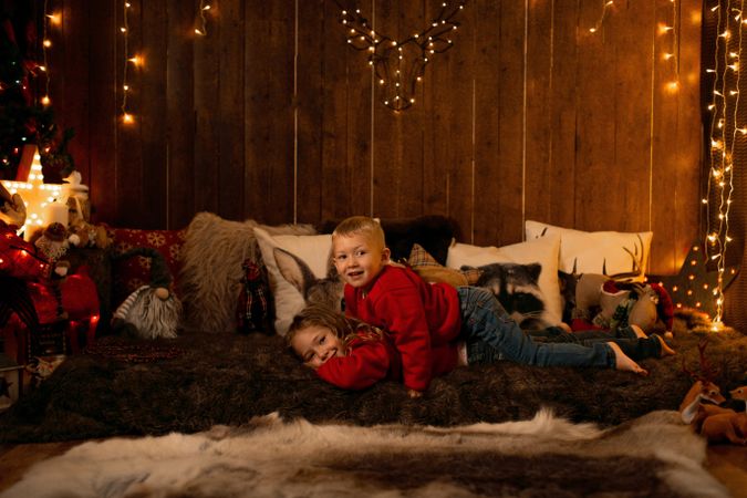 Siblings lying down in a room with christmas decoration