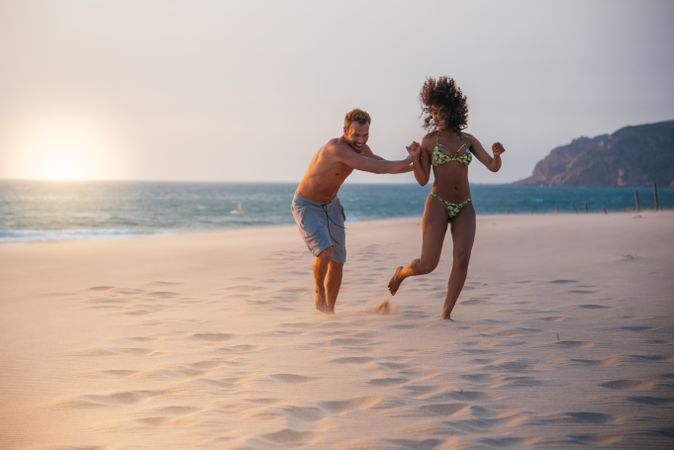 Happy couple running on tropical romantic beach