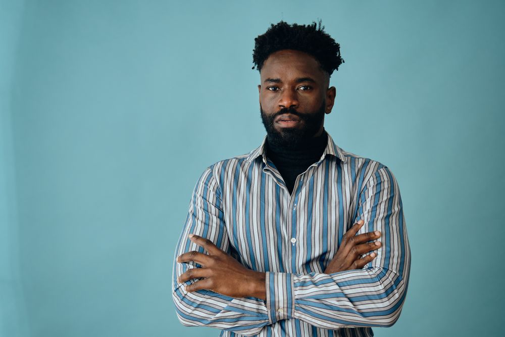 Serious Black man wearing striped shirt with his arms crossed
