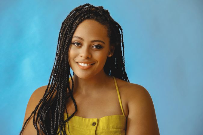 Portrait of happy female with long braided hair in yellow clothes