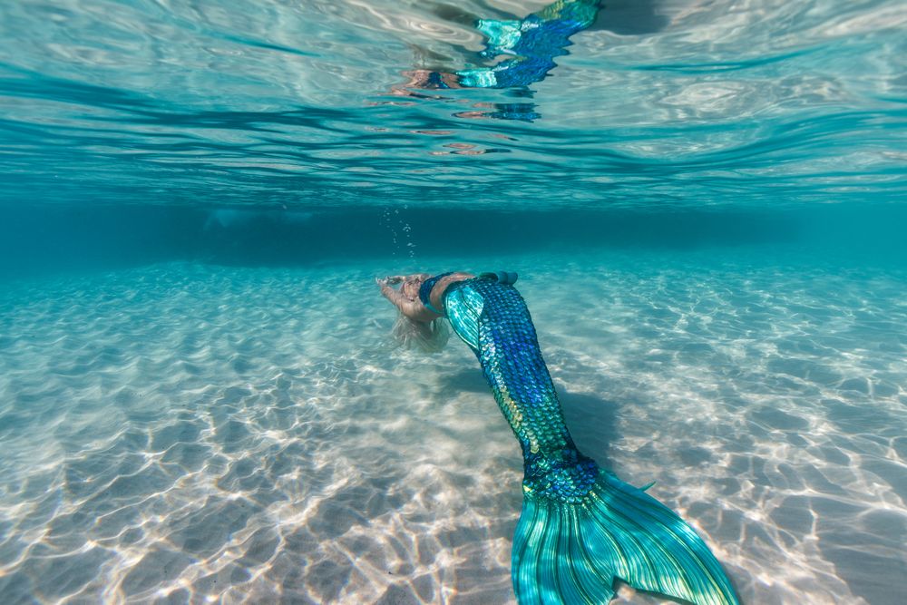 Blond fairytale female mermaid swimming underwater