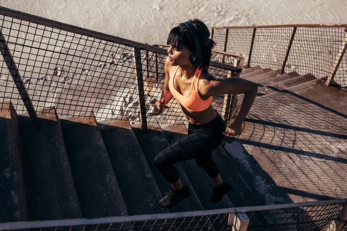 Fitness woman running up the stairway along the beach