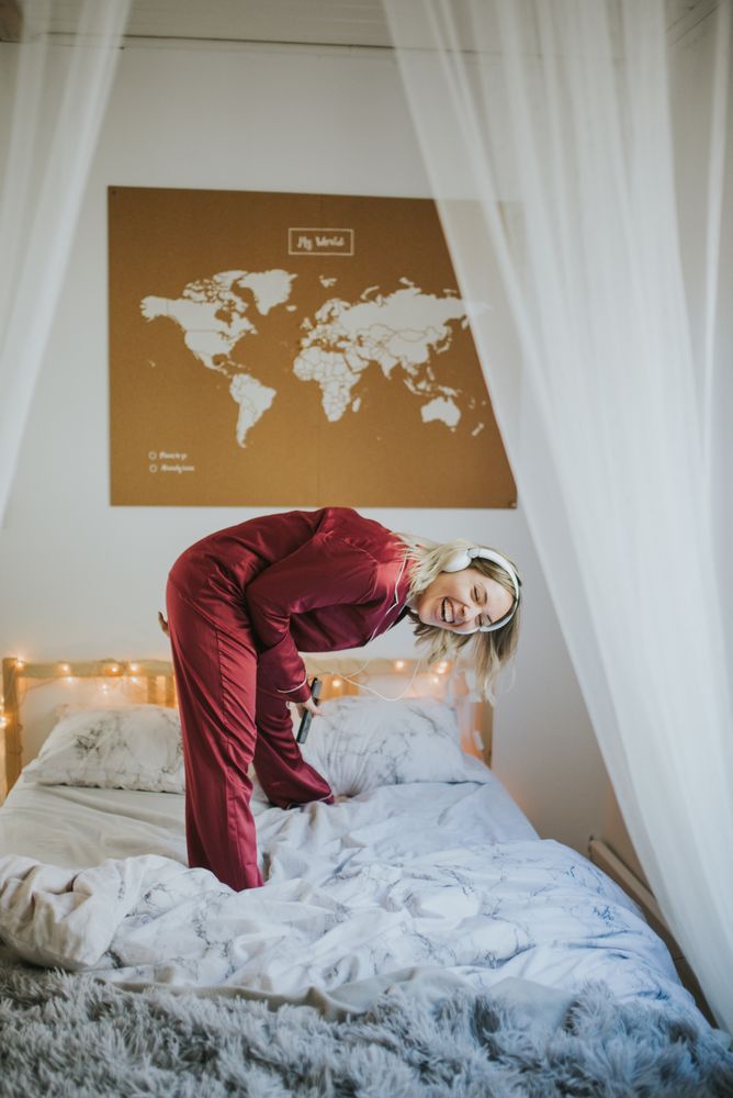 Woman with headphones dancing in bed