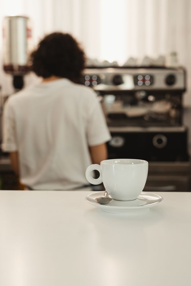 Cup of coffee on counter with barista in background
