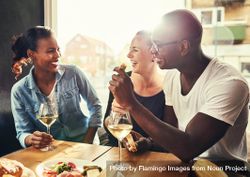 Multi-ethnic group smiling in a restaurant with wine and snacks 4drQQ0