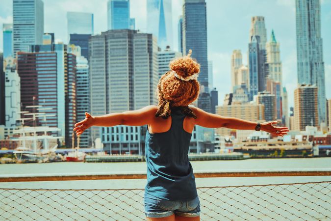 Black woman facing the Hudson River in the background with her arms opened