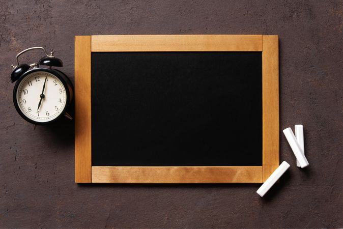 Wooden framed writing board surrounded with clock and chalk