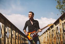 Man with guitar standing on bridge