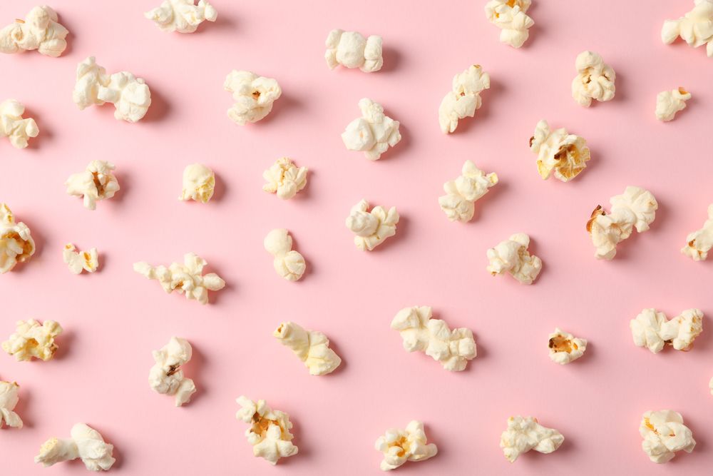 Flat lay composition with popcorn on pink background, closeup
