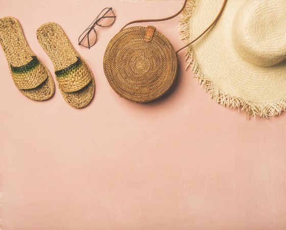 Sandals, glasses, bag, straw hat on pink background, with copy space