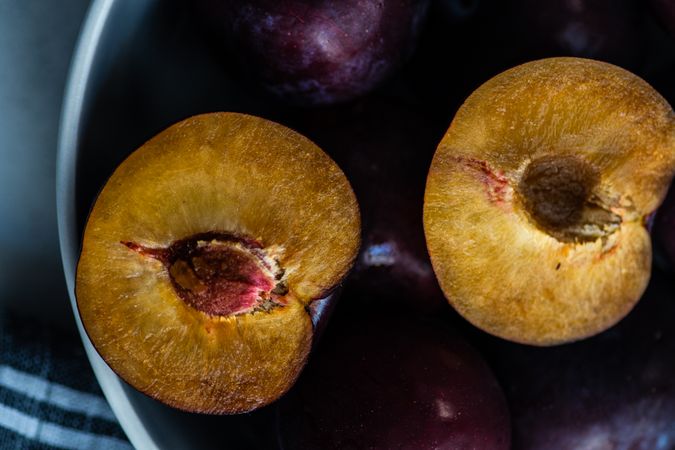 Halved ripe plums in a bowl